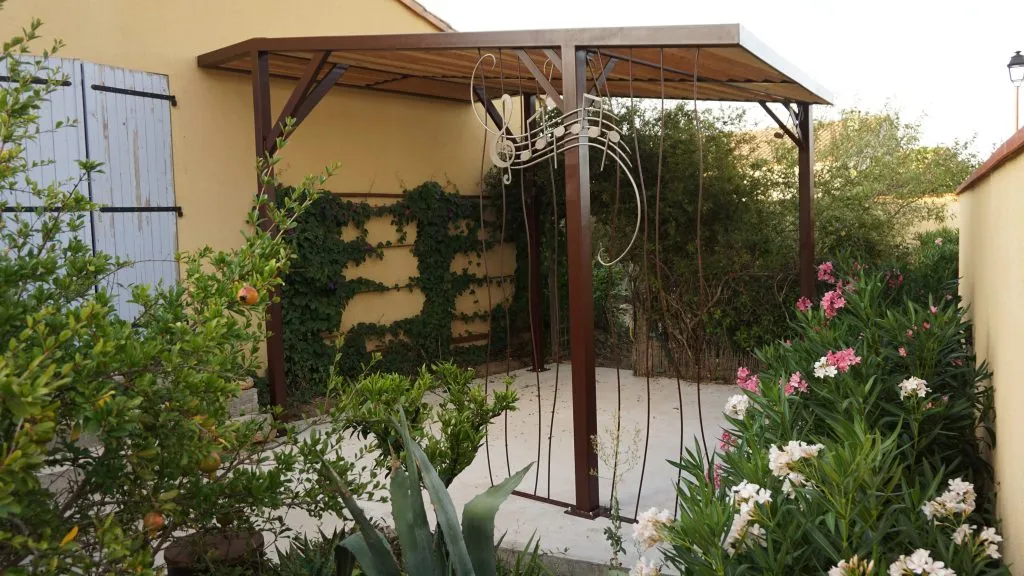 Pergola acier dans jardin fleuri